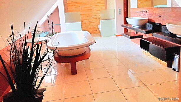 Un baño moderno con una bañera independiente, un tocador de madera y un espejo grande.