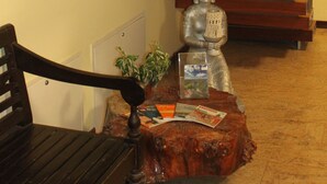 Una escalera con escalones de madera y barandilla de metal, un banco de madera, una estatua de Buda y una mesita con una planta y revistas.