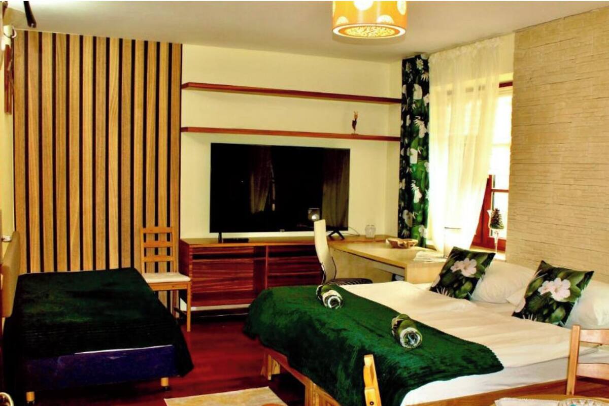 Habitació d'hotel amb llit, escriptori, cadira i televisió.