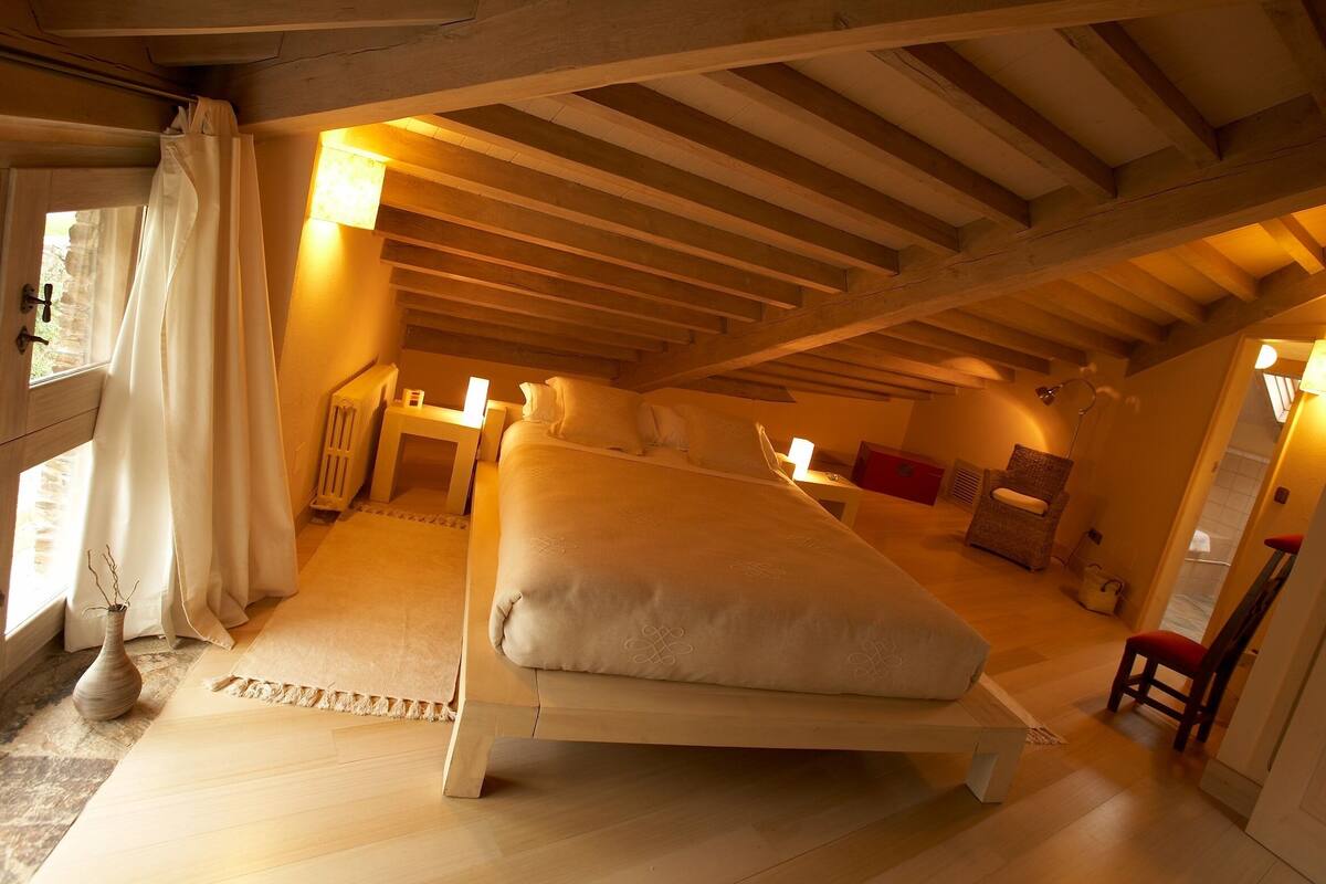 Une chambre confortable située dans les combles, avec un grand lit, une petite table et une chaise.