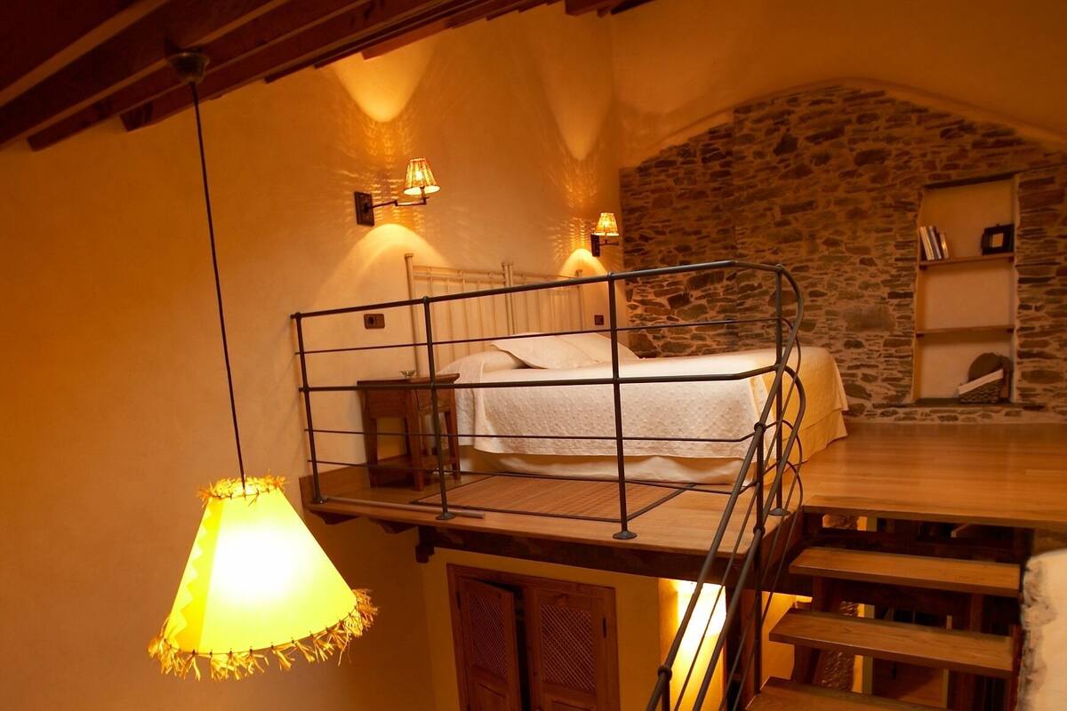Une pièce chaleureuse avec un lit superposé, un bureau en bois et un mur en pierre.