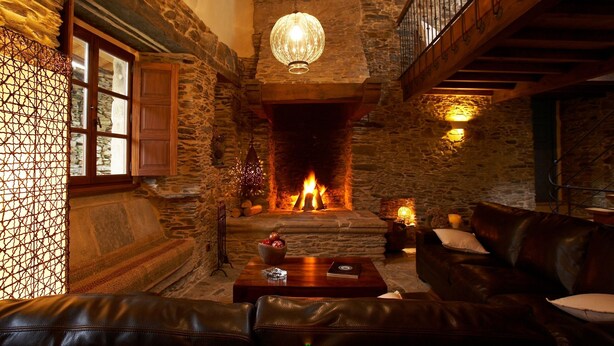 Una habitación acogedora con chimenea de piedra, mobiliario de cuero y una escalera de madera.