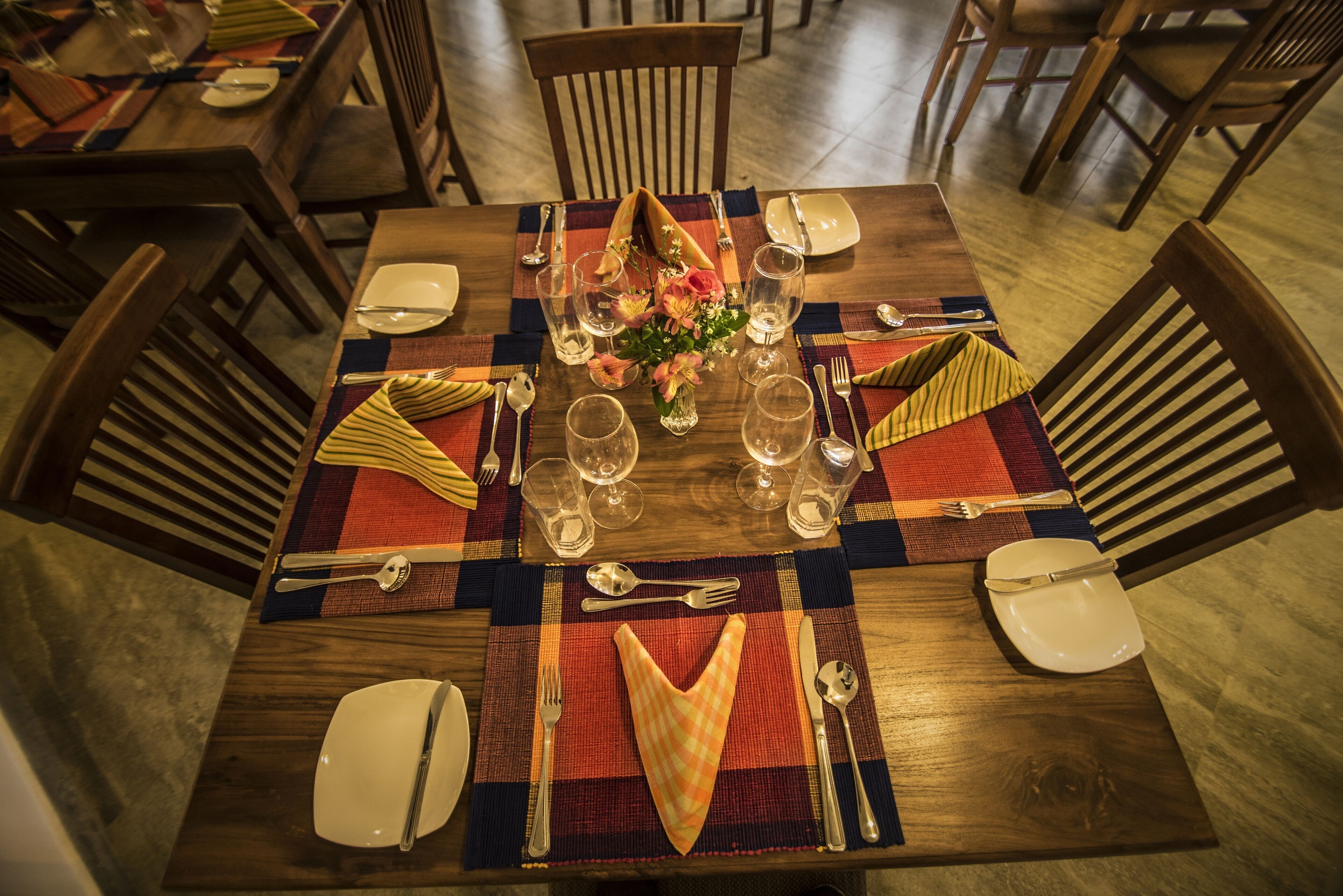 A dining table set with cutlery, glasses, and a centerpiece.