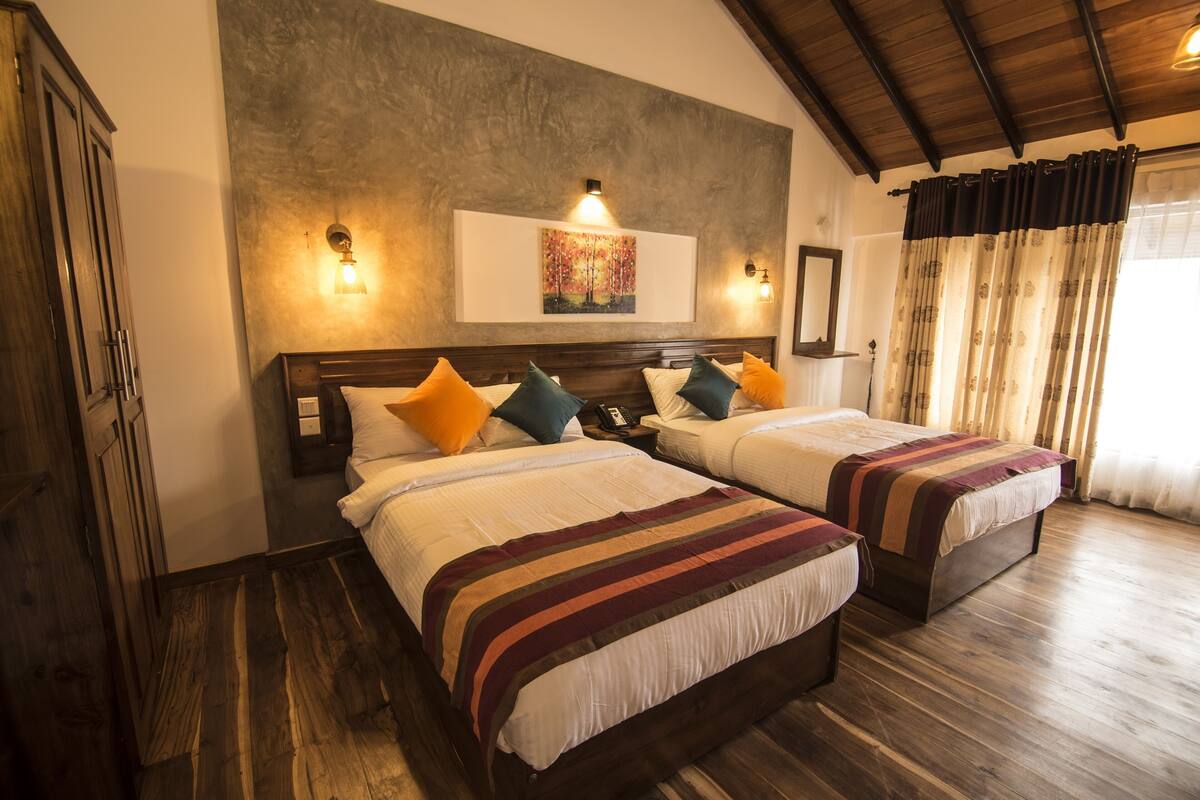 A hotel room with two beds, wooden flooring, a large painting on the wall, and a wooden ceiling.