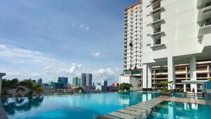 A rooftop infinity pool with a city skyline view, surrounded by a modern building with multiple balconies. - Ais Kacang Sweet Home Pinnacle Tower (Johor Bahru)