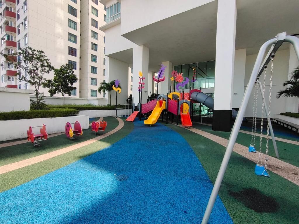 A playground with slides and swings, surrounded by a building with balconies and a pool area.