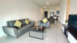 A modern living room with a grey sofa, a glass coffee table, and a flat-screen TV. - Ais Kacang Sweet Home Pinnacle Tower (Johor Bahru)