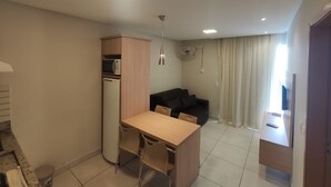 A compact living space with a kitchenette, a dining area, a sofa, and a TV.