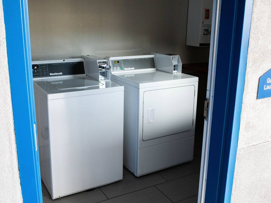 A laundry area with two front-loading machines and a sign indicating 'Guest Laundry'.