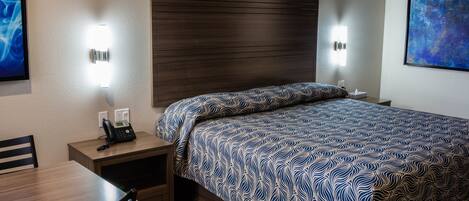 Una habitación de hotel con una cama grande, mesitas de noche, un escritorio y sillas.