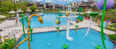 A swimming pool with colorful water features and a cityscape in the background.