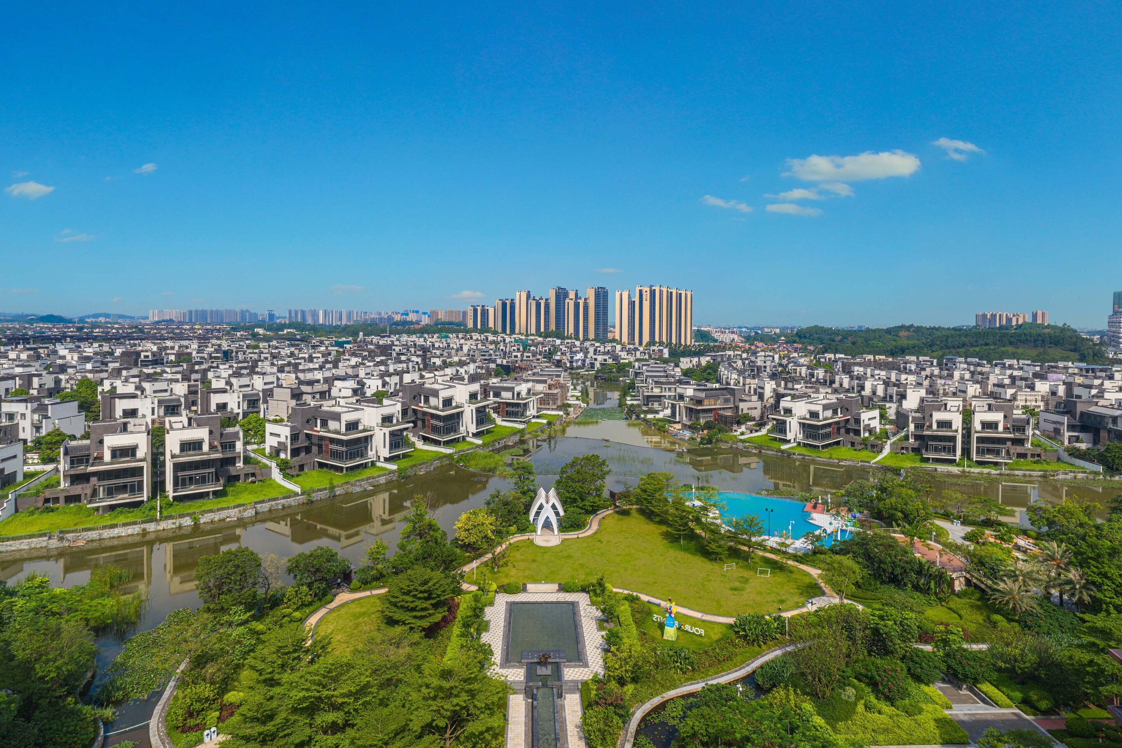 A residential area with modern apartment buildings, a central green space with a fountain, and a swimming pool.