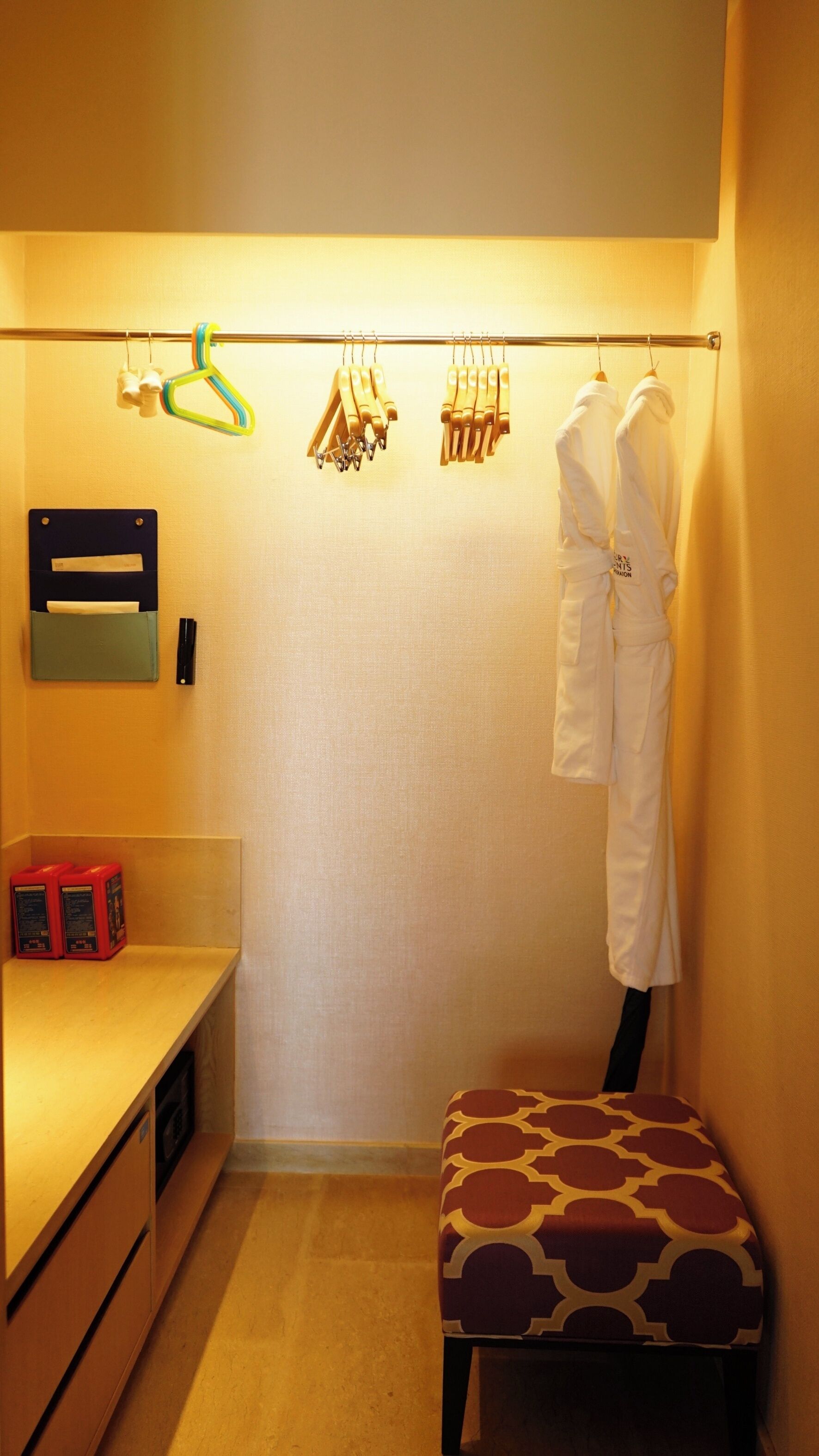 Una habitación pequeña y bien iluminada con un banco, una percha para ropa y un mueble de almacenamiento en la pared.