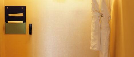 Una habitación pequeña y bien iluminada con un banco, una percha para ropa y un mueble de almacenamiento en la pared.