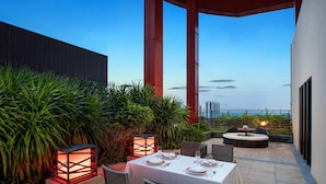 An outdoor dining area with a table set for two, surrounded by greenery and a view of the cityscape. - Four Points by Sheraton Guangdong, Heshan (Jiangmen)