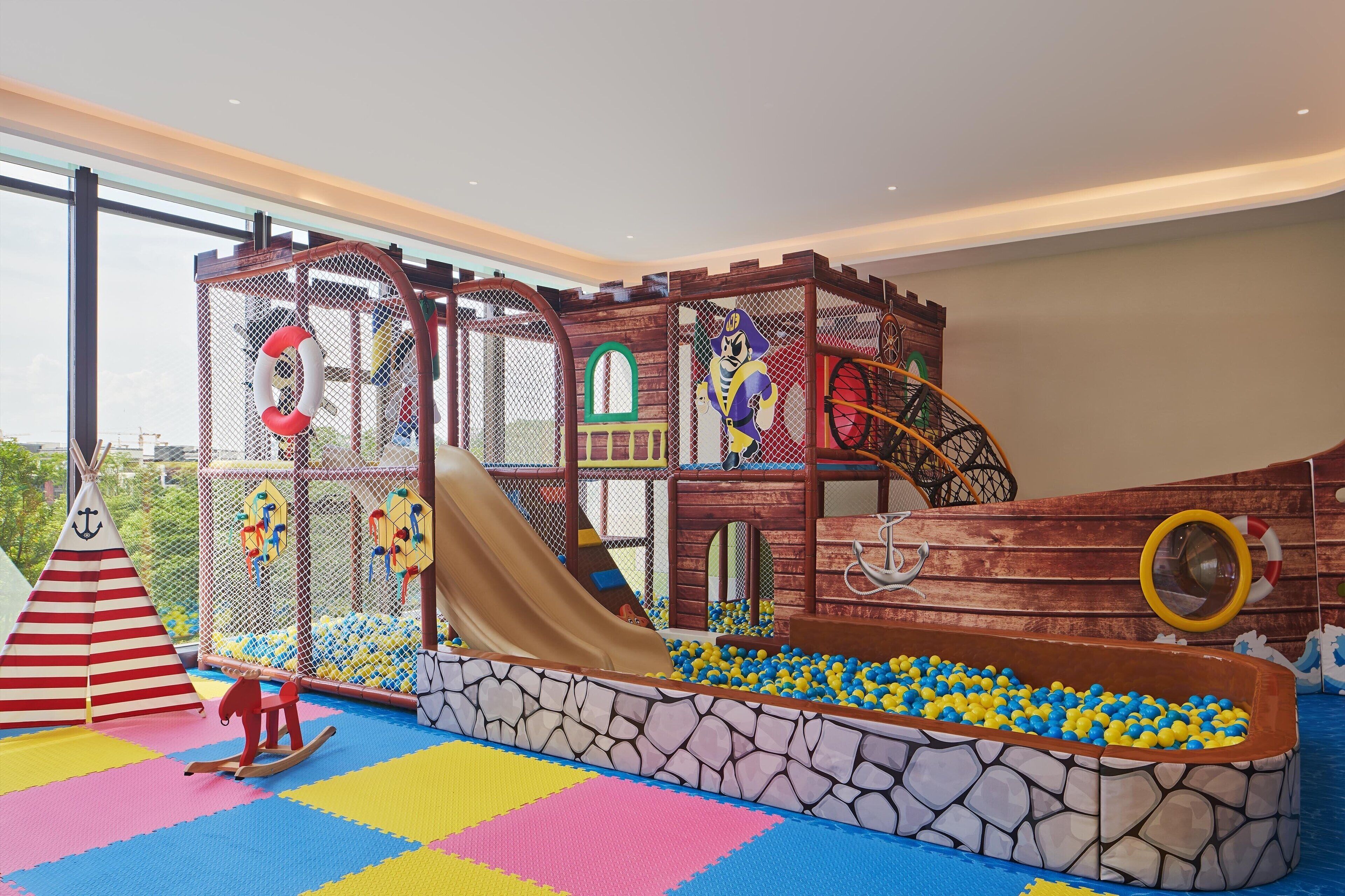 Un espace de jeux avec un toboggan, des structures d’escalade et une piscine à balles.