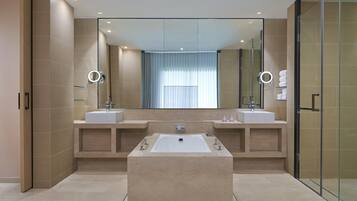 A modern bathroom with two sinks, a large bathtub, and a glass shower enclosure.