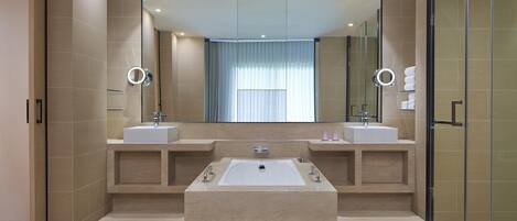 A modern bathroom with two sinks, a large bathtub, and a glass shower enclosure.