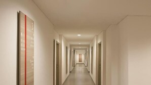 A long, narrow hotel corridor with doors on both sides, leading to individual rooms. - Hotel Amaris Sriwedari Solo (Surakarta)