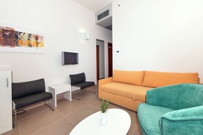 Un salon moderne avec un canapé, un fauteuil, une table basse et un téléviseur.