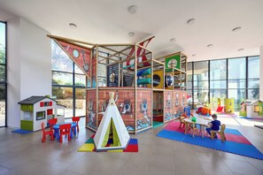 Un espace de jeux comprenant une structure d’escalade, une cabane et une table avec des chaises.