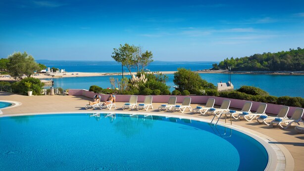 Ein Pool mit Liegestühlen und Meerblick.