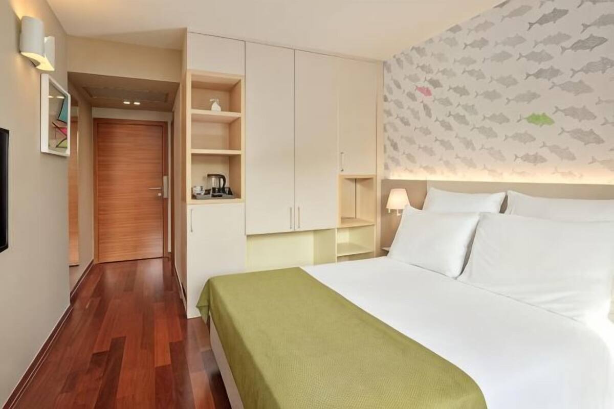 Una habitación de hotel con cama, armario, escritorio y una pared con un motivo de peces.