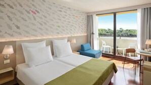 Ein Hotelzimmer mit zwei Betten, einem Balkon mit Blick und einer kleinen Essecke.
