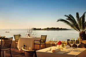 Mesa lista para comer con vista al mar y una palmera.