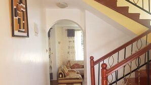 A staircase with a wooden handrail and metal balusters, leading to a living area with a sofa and curtains. - MJ Homestay by Balozi Nairobi (Nairobi)