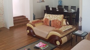 A living room with a sofa, a coffee table with magazines, a dining area with a table and chairs, and a staircase leading to another room. - MJ Homestay by Balozi Nairobi (Nairobi)
