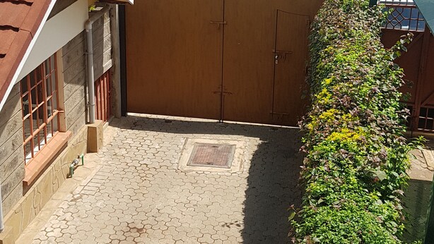 A residential street with houses, a gated driveway, and parked cars. - MJ Homestay by Balozi Nairobi (Nairobi)