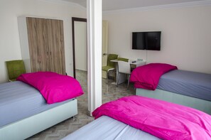 A hotel room with two beds, a desk, a chair, a television, and a wardrobe. - Venüs Pansiyon (Çanakkale)