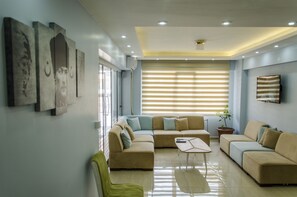 A modern living room with a sectional sofa, a coffee table, and artwork on the walls. - Venüs Pansiyon (Çanakkale)