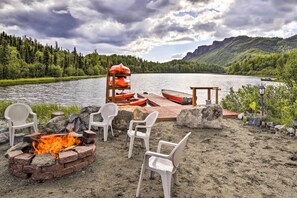 A lakeside deck with a fire pit, chairs, and a canoe. - Lodge 88: Lakefront, Dock, Boats & Wildlife (Chickaloon)