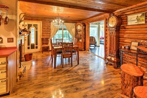 Interior de madeira com área de jantar, um grande relógio de madeira e um lustre.