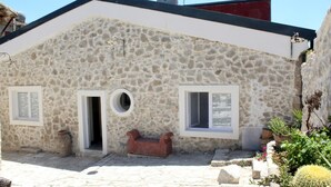 A stone building with two windows, a door, and a small bench.