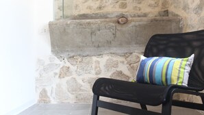 A black metal chair with a striped cushion against a stone wall.