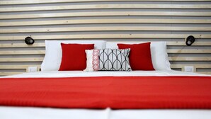 A bed with a red and white bedspread, two red pillows, and a patterned pillow.