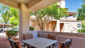 Une terrasse extérieure avec une table et six chaises à rayures, entourée d’un petit muret et d’arbres.