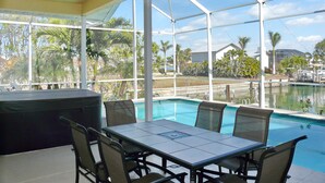 A covered outdoor area with a pool, seating, and a ceiling fan. - Beautiful Water Views, 5-min Walk to South Beach, Heated Pool, Hot Tub, 5 Bikes (Marco Island)