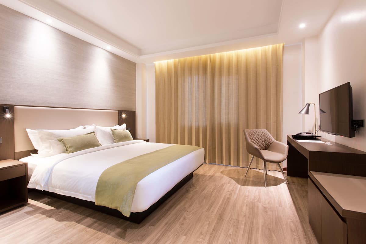 Una habitación de hotel moderna con una cama grande, un escritorio, una silla y un televisor.
