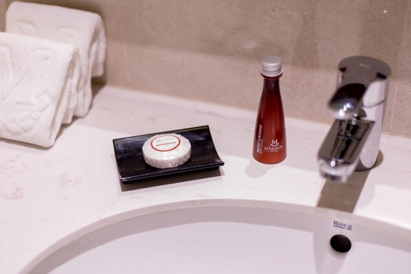 Un lavabo de salle de bain avec un flacon de lotion, un savon et des serviettes pliées.