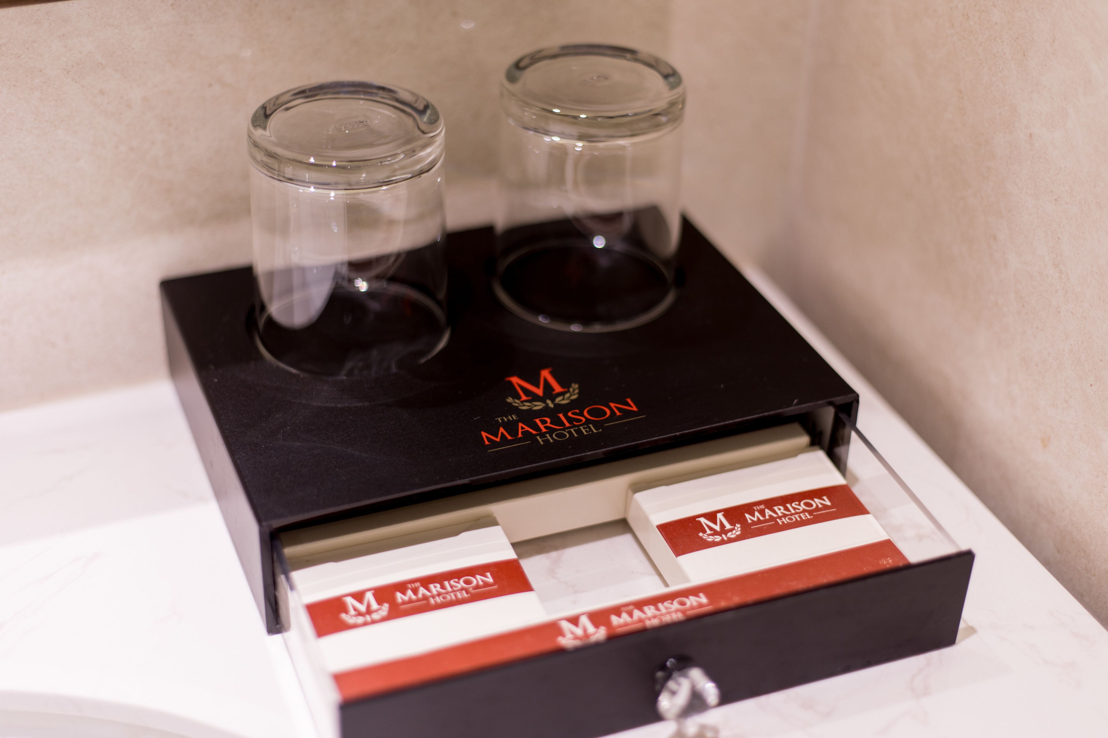 Een minibar met twee glaasjes en drie flesjes drank.