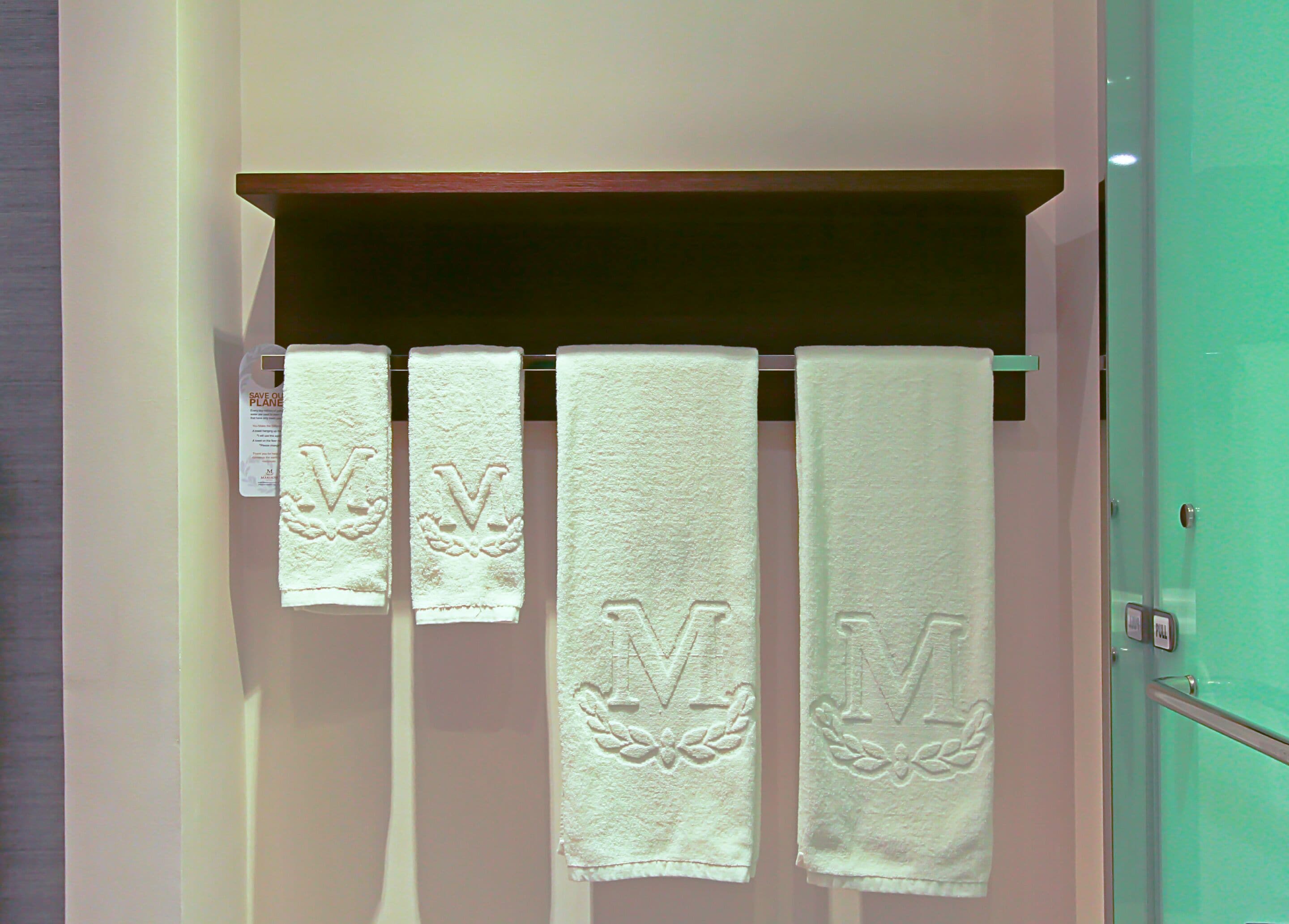 A bathroom with four towels hanging on a rack, each with a monogram.