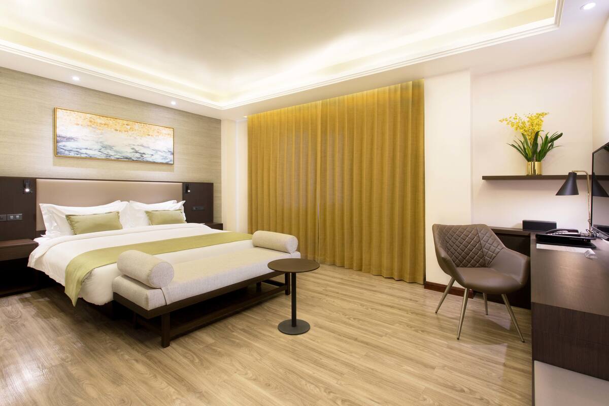 Una habitación de hotel moderna con una cama grande, un escritorio, una silla y una mesita.