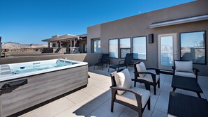 Eine Dachterrasse mit Whirlpool, Sitzgelegenheiten im Freien und großen Fenstern mit Blick auf die Stadt.