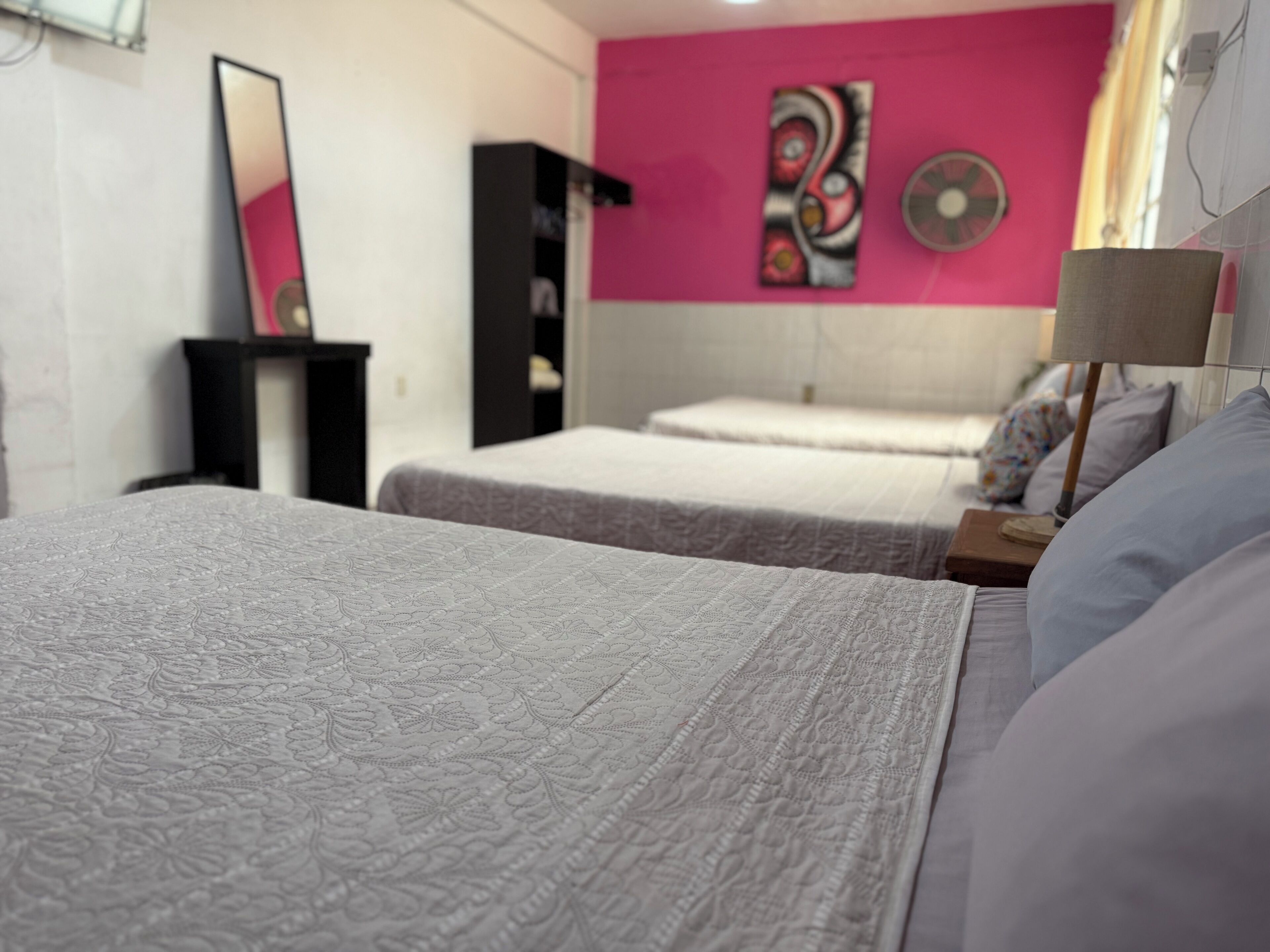 Een hotelkamer met twee bedden, een grote spiegel, een schilderij aan de muur en een lampje op het nachtkastje.