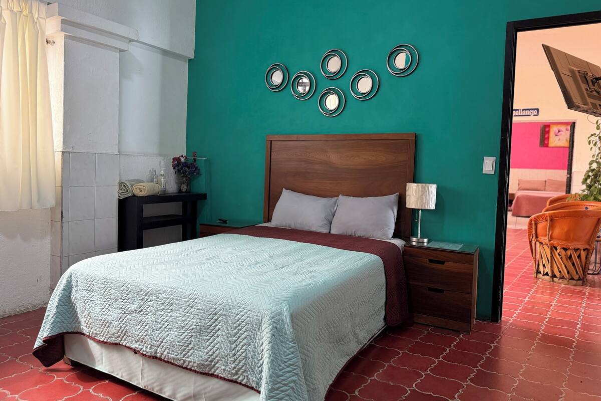 A bedroom with a bed, nightstands, a lamp, and a wall with circular mirrors.