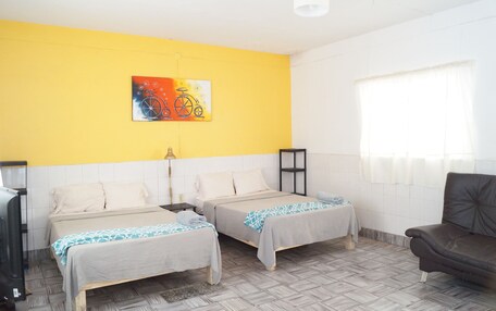 A room with two beds, a sofa, a painting on the wall, and a window with curtains.